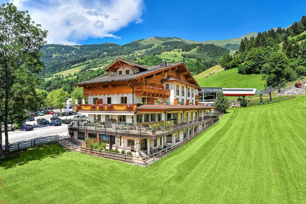 une vue sur une grande maison sur un champ verdoyant dans l'établissement Aktivhotel Gasteiner Einkehr, à Dorfgastein