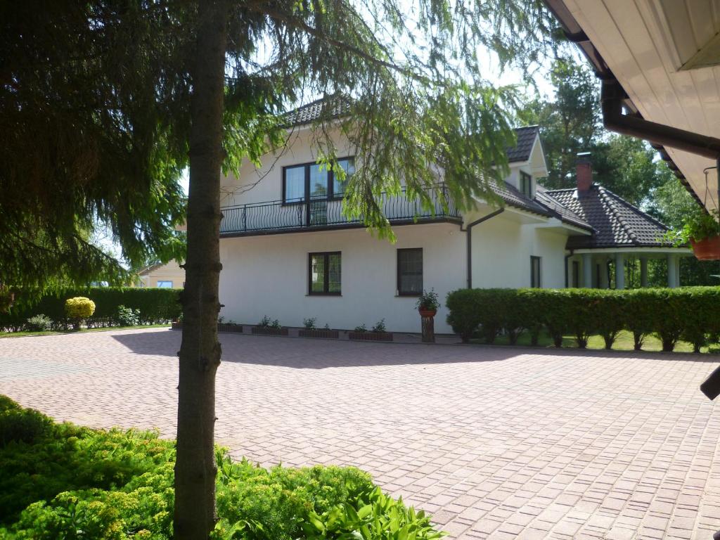 a large white house with a brick driveway at Pokoje Gościnne Wajer in Bobolin