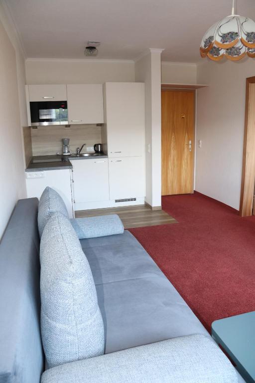 Una sala de estar con un sofá y una cocina. en Pension Bichlgeiger, en Anras