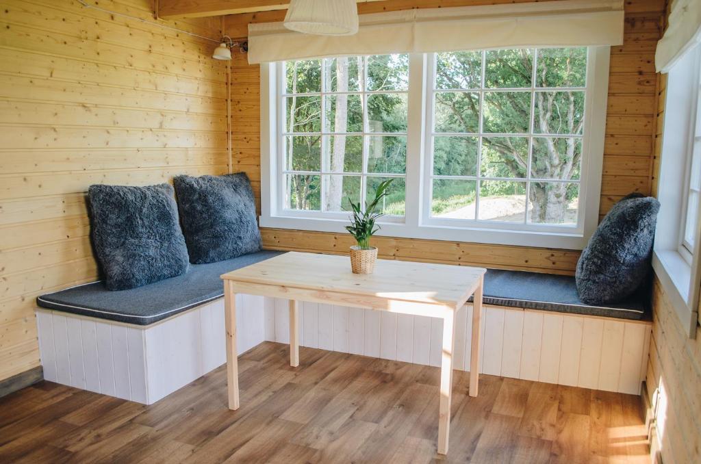 Habitación con mesa, cojines azules y ventana. en Bārtas Krasts, en Dunika