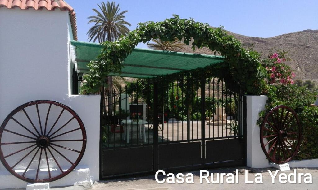 una puerta con una rueda de carruaje al lado de un edificio en Casa Rural La Yedra, en Níjar