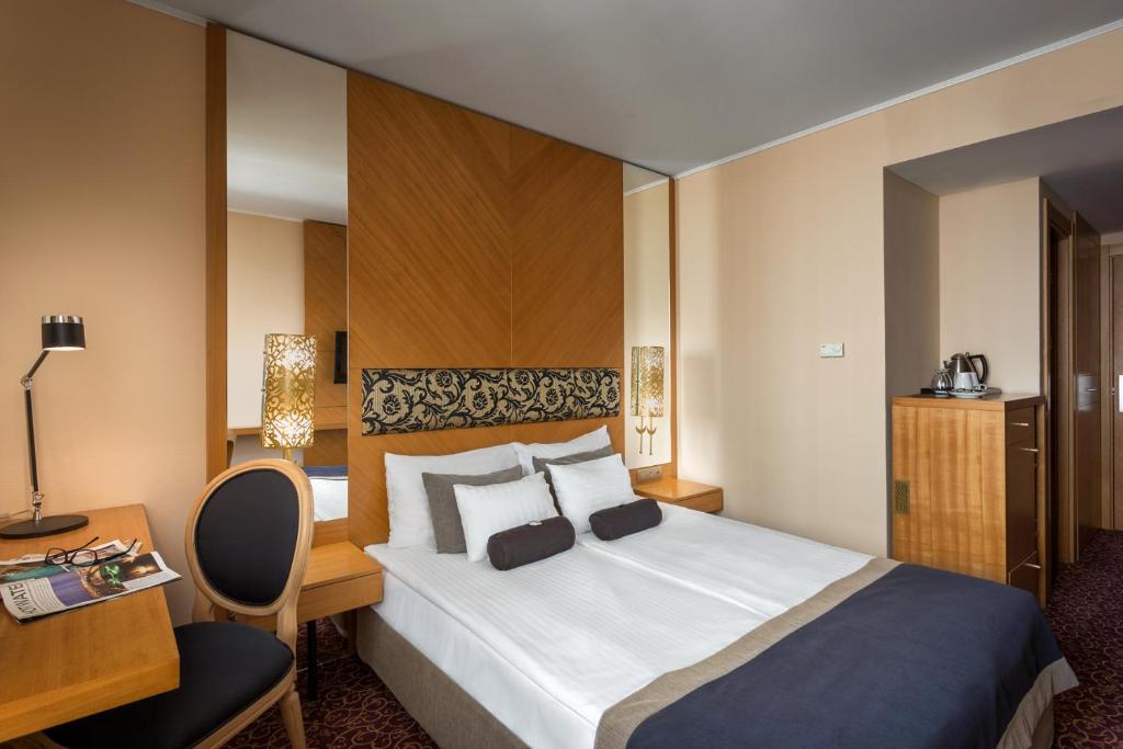 a hotel room with a bed, chair, and nightstand at Marmara Hotel Budapest in Budapest