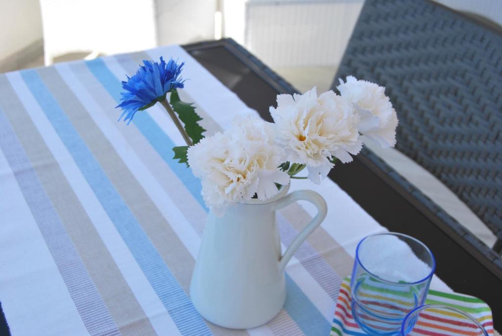 un vaso bianco con fiori bianchi e blu su un tavolo di Venti d'aMare a Marina di Modica