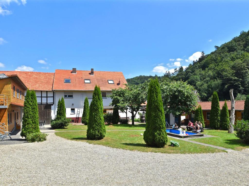 バート・ヴィルドゥンゲンにあるHoliday farm situated next to the Kellerwald Edersee national park with a sunbathing lawnの木々の庭とスイミングプールのある家