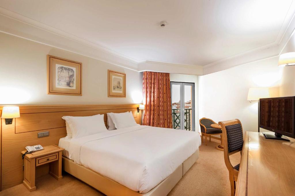 a hotel room with a bed and a television at Hotel Real Palacio in Lisbon