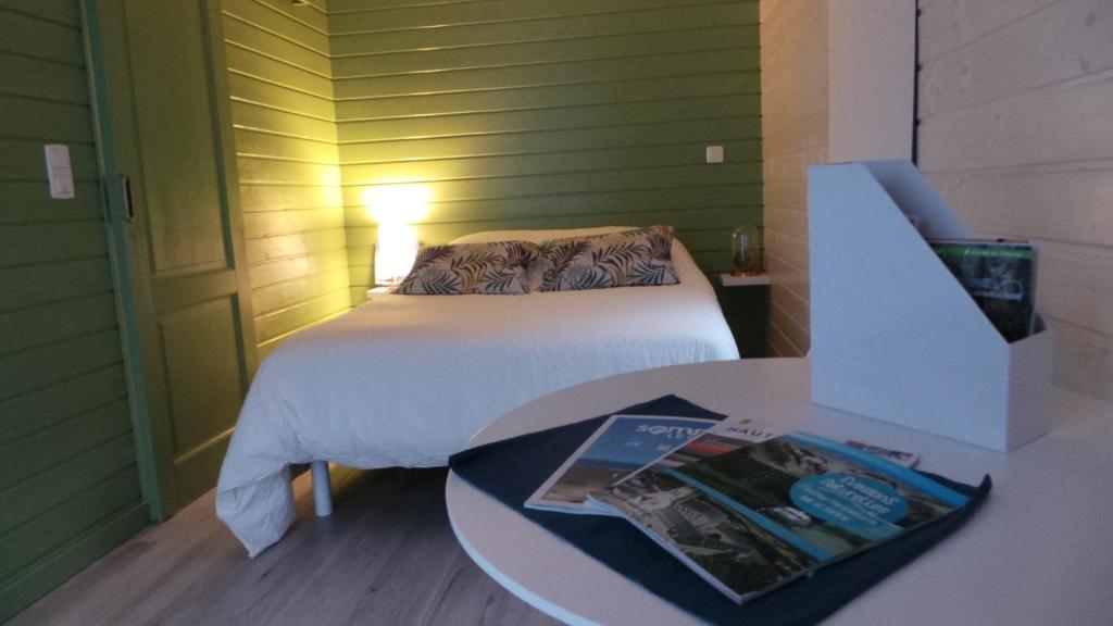 a room with a bed and a table with a book at Au Cap Norwoe in Saint-Quentin-en-Tourmont
