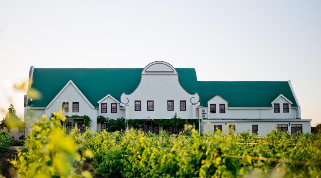 ein großes weißes Haus mit grünem Dach in der Unterkunft Cana Vineyard Guesthouse in Paarl