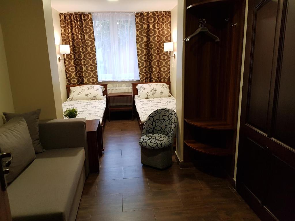 a hallway with two beds and a couch and a window at Marcus in Bydgoszcz