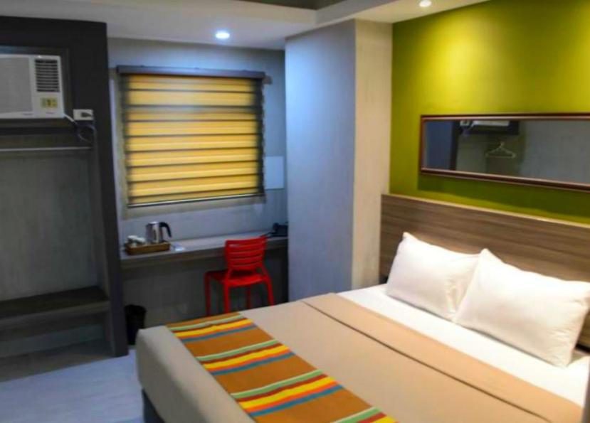 1 dormitorio con 1 cama y 1 silla roja en Express Inn Cebu Osmena, en Cebú