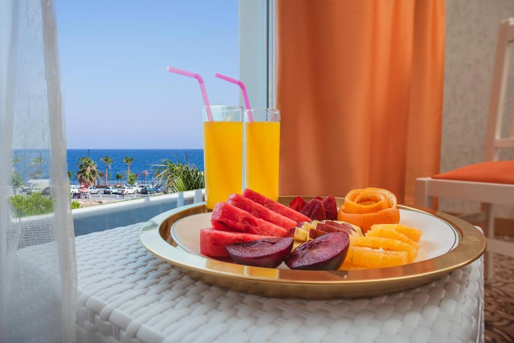 a plate of fruit on a table with a drink at Golden Orange Hotel in Antalya