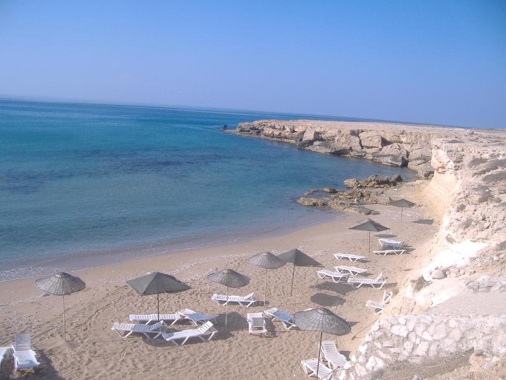 uma praia com guarda-sóis e cadeiras e o oceano em Theresa Hotel at Karpaz Peninsula em Ayia Trias