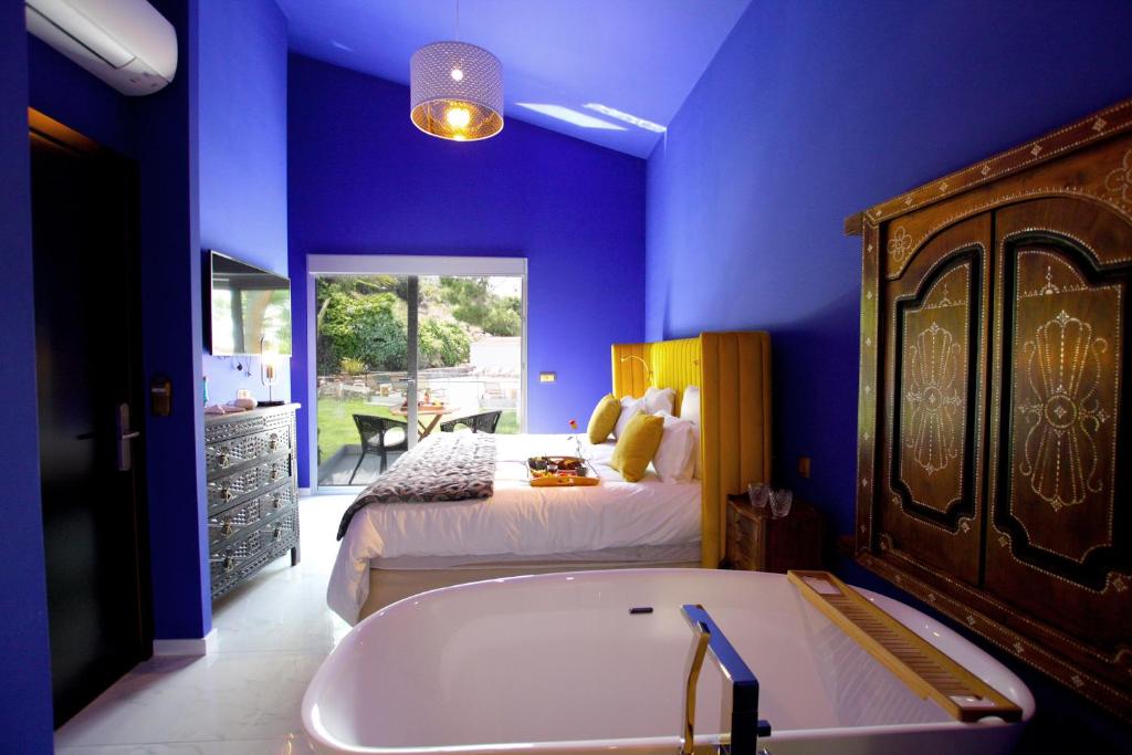 a blue bedroom with a bed and a tub in it at Hotel Minera in Monticello