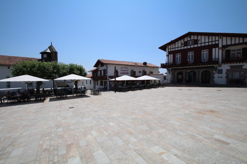 une grande cour avec des tables et des parasols dans un bâtiment dans l'établissement Hotel Restaurant Elissaldia, à Bidart