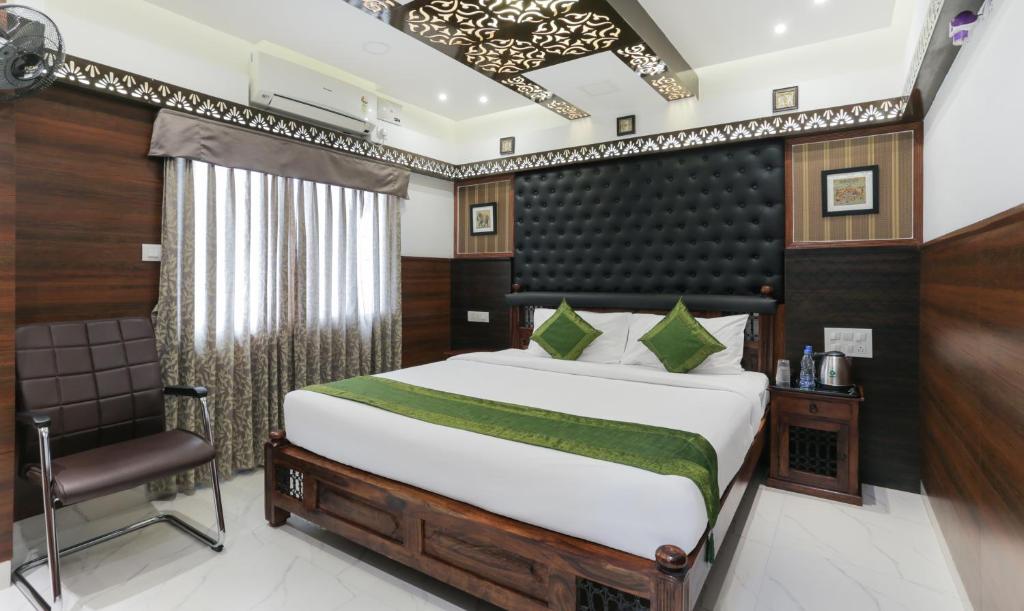 a bedroom with a bed and a chair at Hotel Dvaraka Inn in Bengaluru