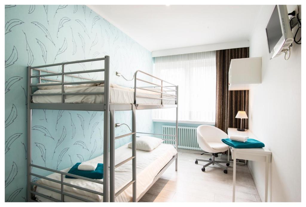 een slaapkamer met 2 stapelbedden en een bureau bij Hotel Ter Streep in Oostende