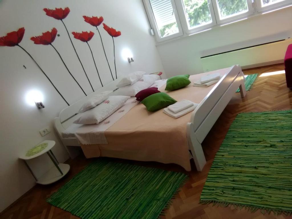 a bedroom with a bed with red flowers on the wall at Apartment Calluna in Split