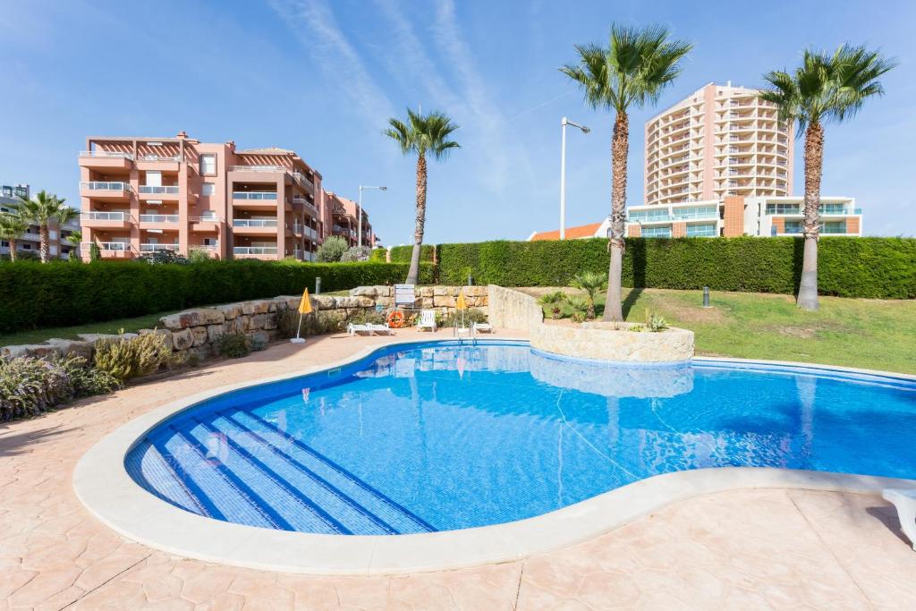 - une piscine bordée de palmiers et de bâtiments dans l'établissement Tropical Beach Apartment Litoralmar, à Portimão