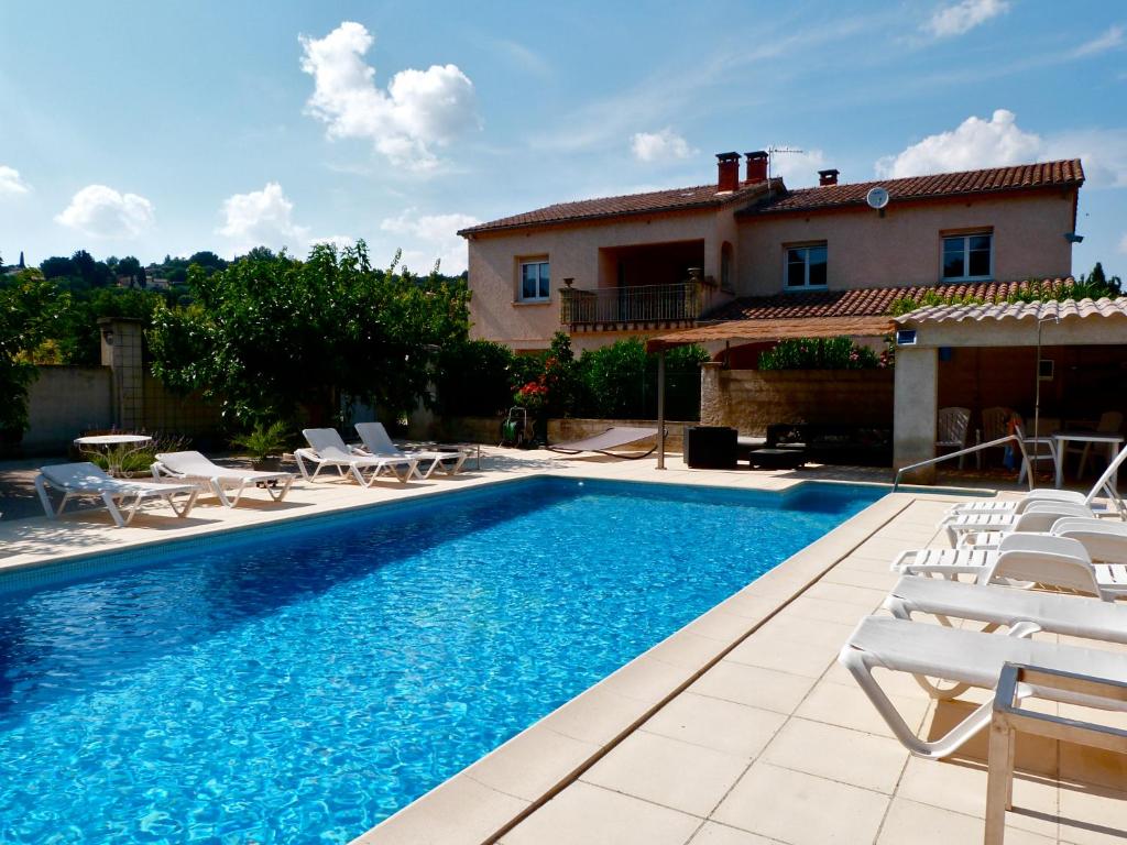 a swimming pool with white chairs and a house at Appartement Salvaterra in Sauveterre