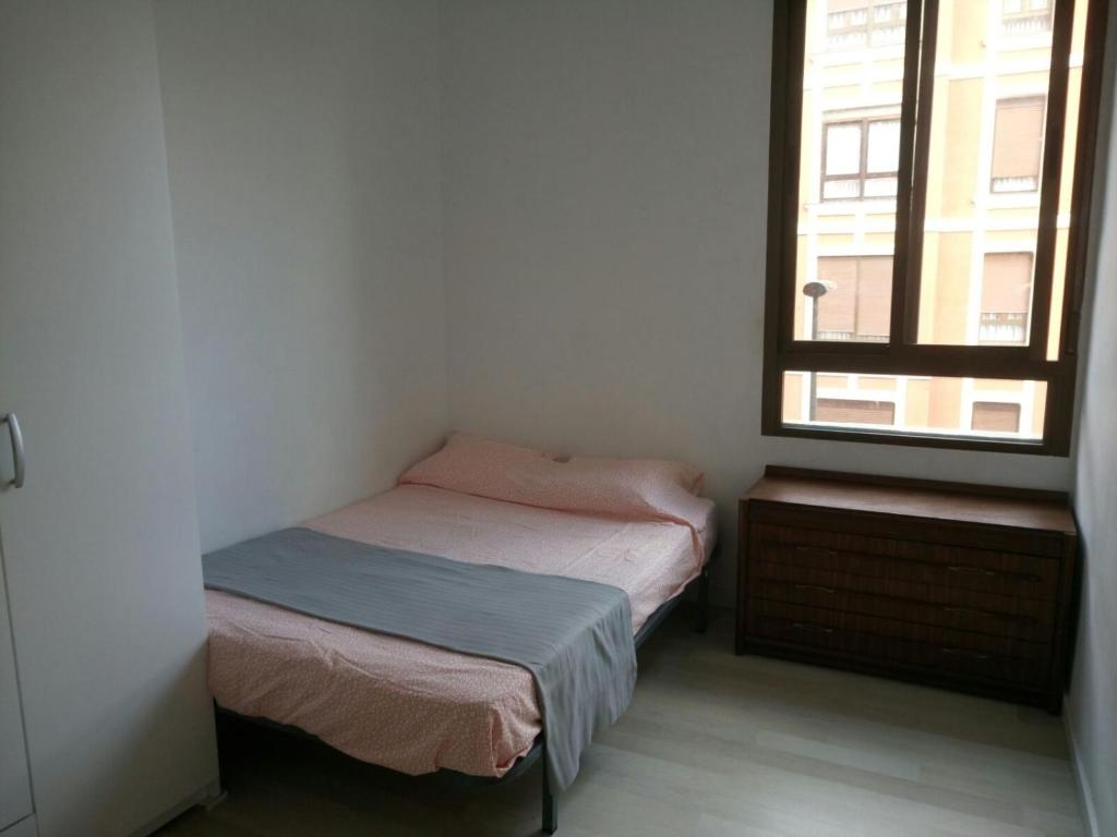 a small bedroom with two beds and a window at Bilbao habitaciones in Bilbao