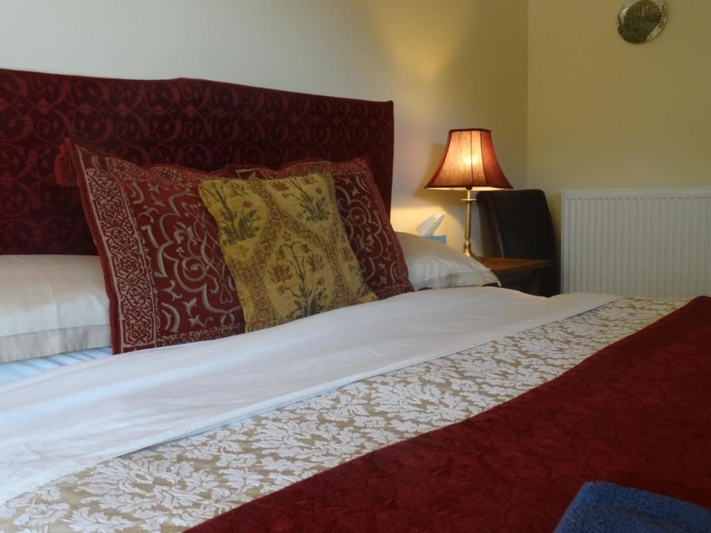 a bed with red and white pillows and a lamp at Middle Woodbatch B&B in Bishops Castle