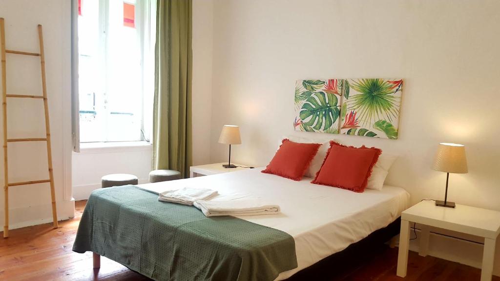 リスボンにあるBmyT Central Apartmentsのベッドルーム1室(赤い枕と絵画付)