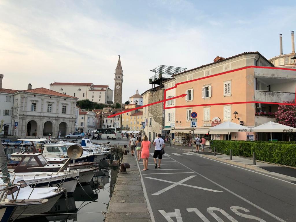a group of people walking down a street next to boats at Gloria Holiday - Apartment Rebecca in Piran