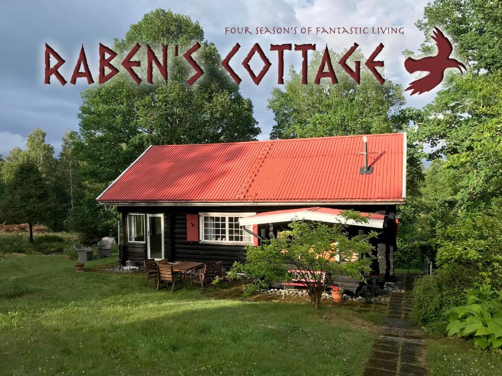 ein kleines Haus mit rotem Dach und einem Schild in der Unterkunft Rabens Cottage in Bengtsfors
