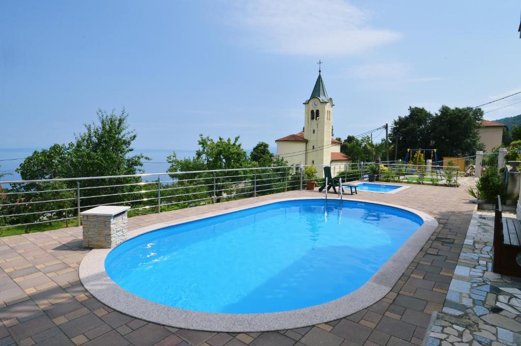 a swimming pool with a church in the background at Apartments Krupic in Opatija