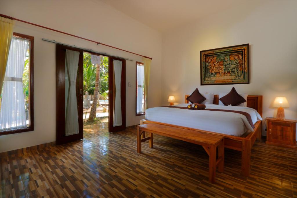 Crystal Bay Villa & Residence في نوسا بينيدا: غرفة نوم بسرير كبير وارضية خشبية