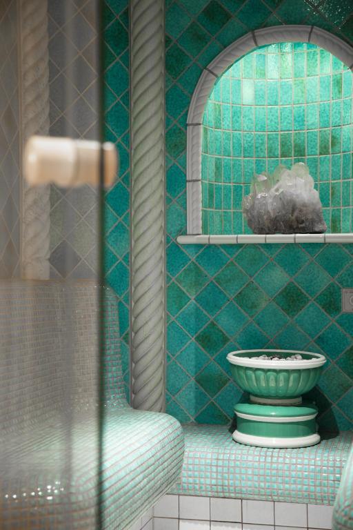 a green tiled bathroom with a sink and a mirror at Superior Hotel Tirolerhof - Zell am See in Zell am See