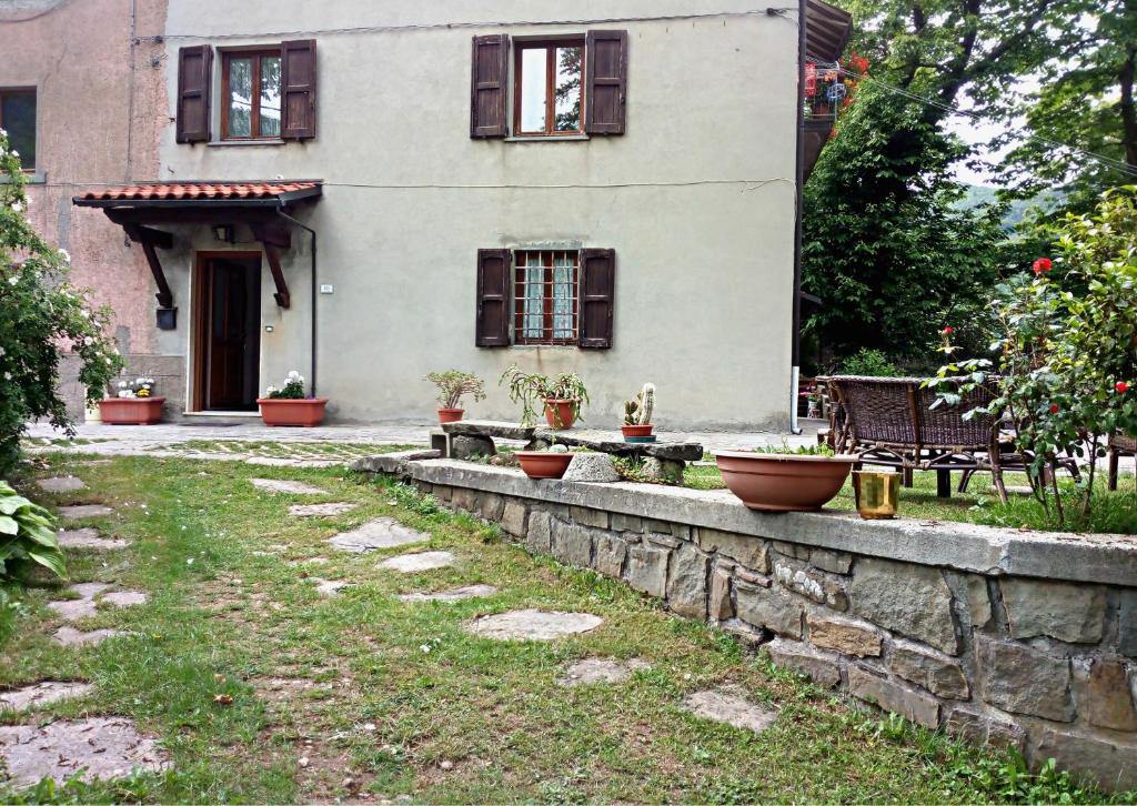 a house with a stone wall in front of a yard at A Casa di Nonna in Pian degli Ontani