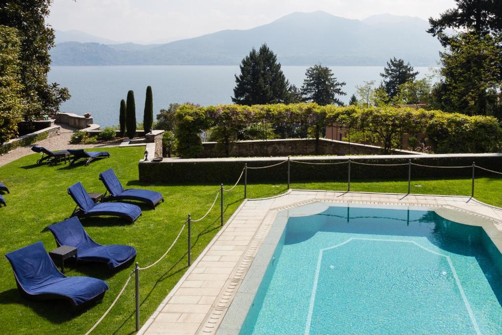 a swimming pool in a yard with blue chairs and the water at Relais Villa Margherita in Oggebbio