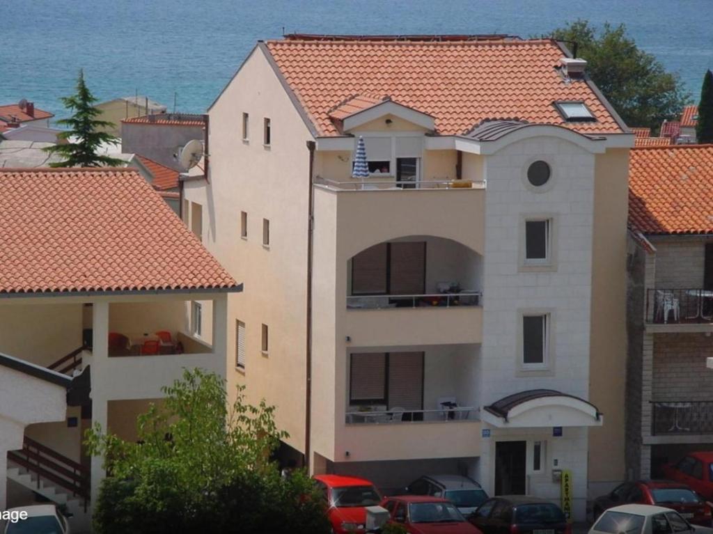 un grand bâtiment avec un toit en tuiles rouges dans l'établissement Apartments Juric, à Baška Voda