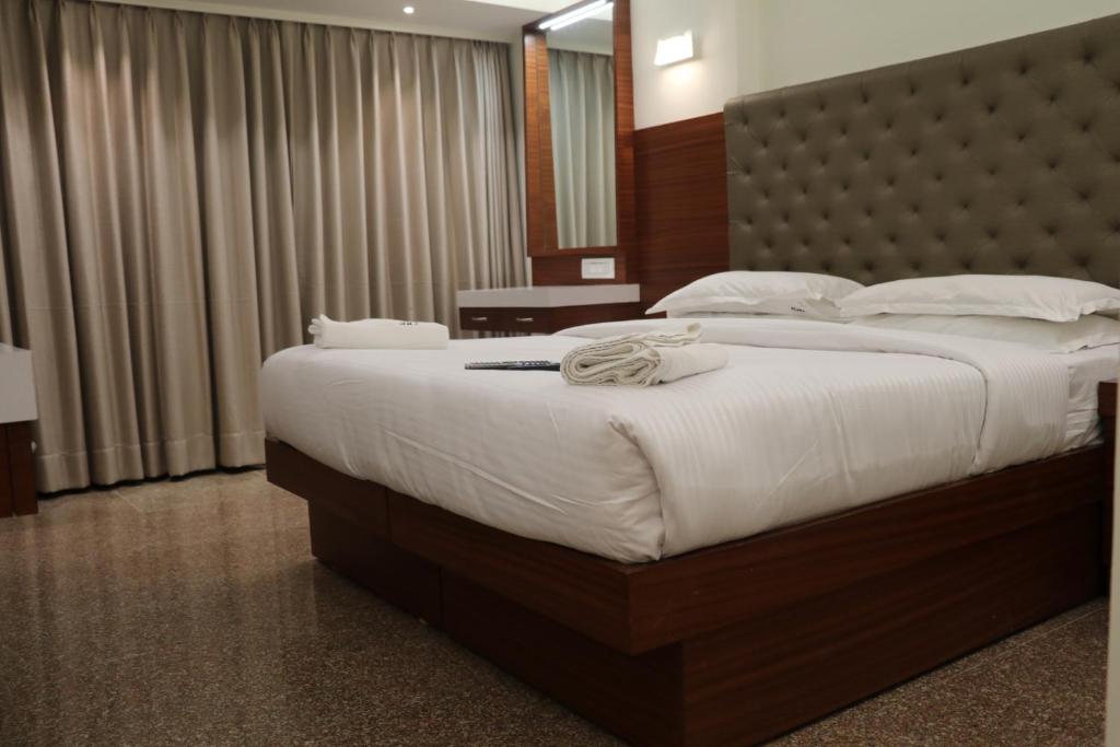 a bedroom with a large bed with white sheets at Hotel Milan International in Mumbai
