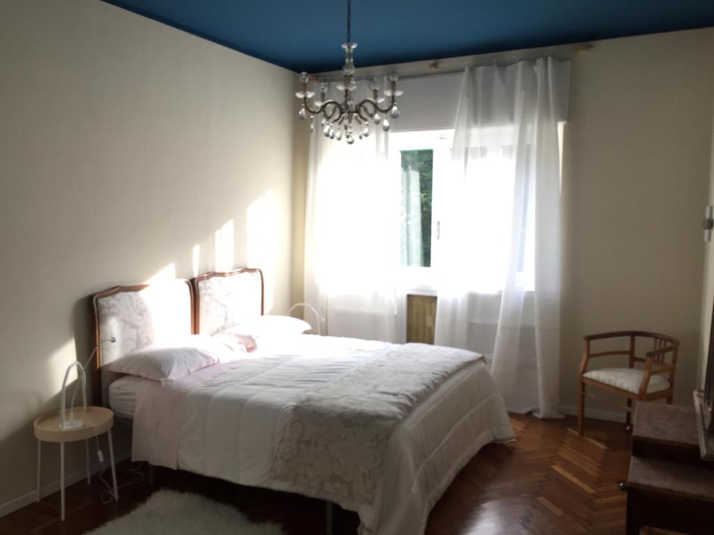 ein Schlafzimmer mit einem Bett mit einem Kronleuchter und einem Fenster in der Unterkunft Beaucoeur in Aosta