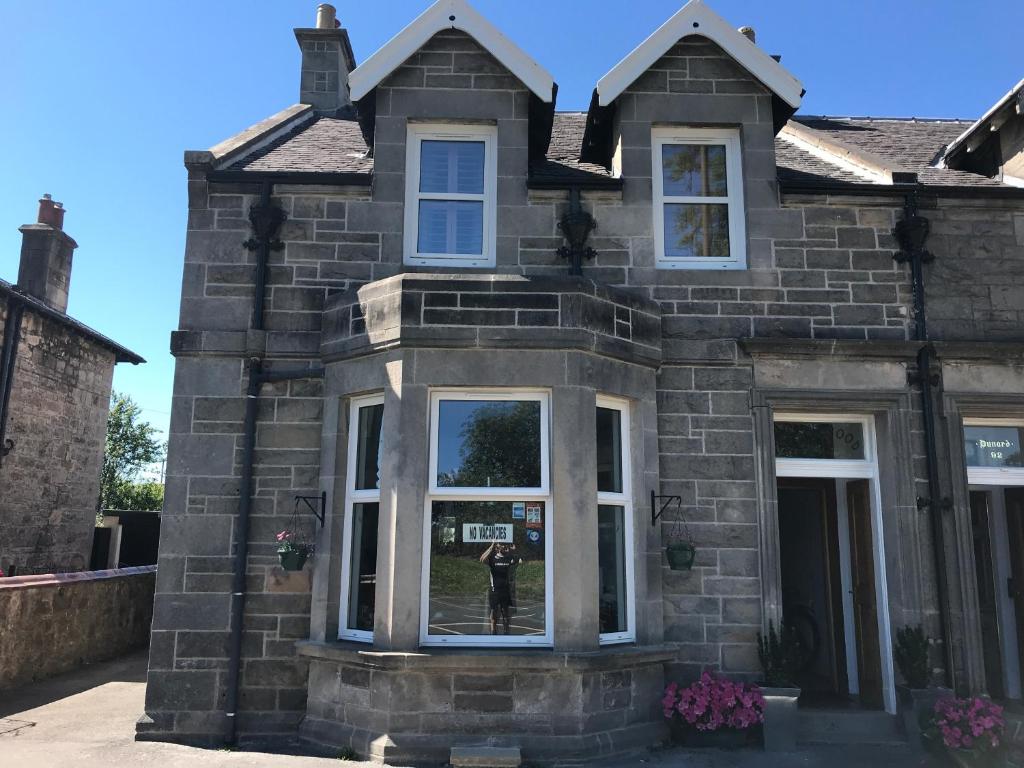 a brick house with a person in the window at Ravenswood Guest House in Stirling