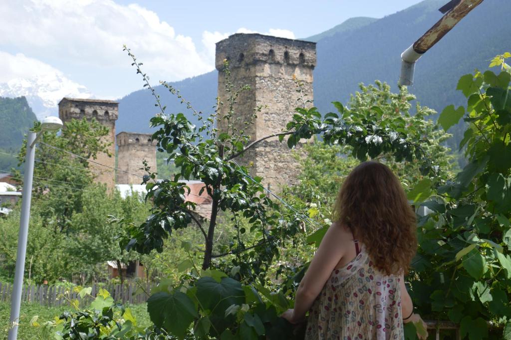 Una donna in piedi di fronte a un castello di Ailama Guesthouse a Mestia
