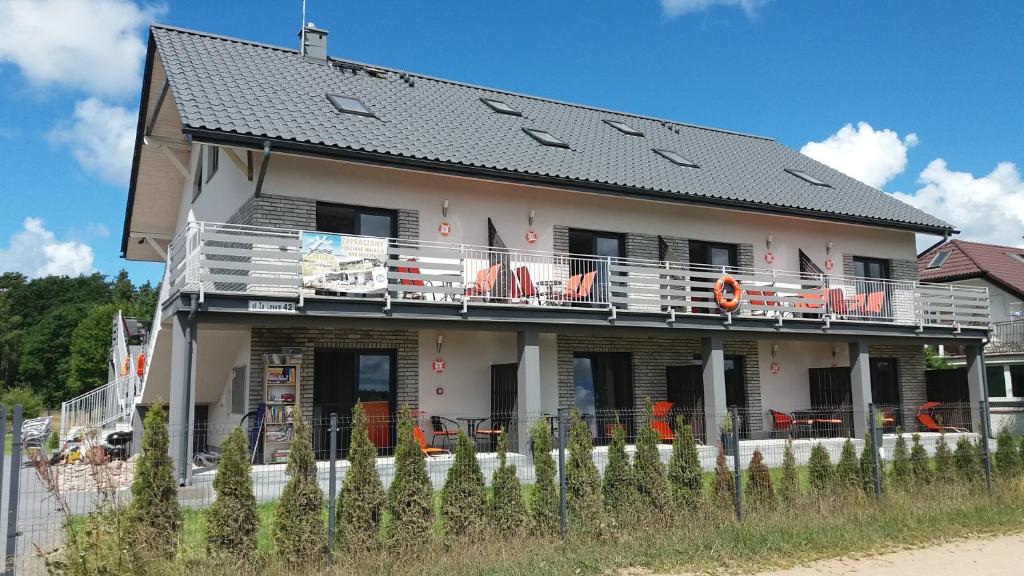 una casa con un balcón con sillas naranjas. en Amber Jarosławiec, en Jarosławiec