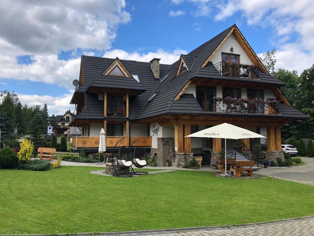 una casa con techo de gambrel en un césped en Willa Ryś, en Zakopane