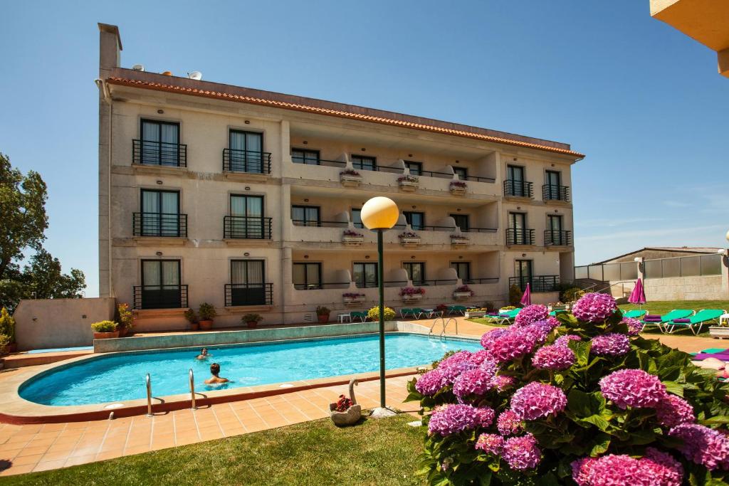 un hotel con piscina frente a un edificio en Hotel Oca Vermar, en Aios