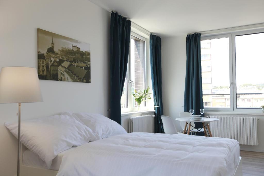 a white bedroom with a white bed and windows at City Center Best Place Apartments in Bratislava