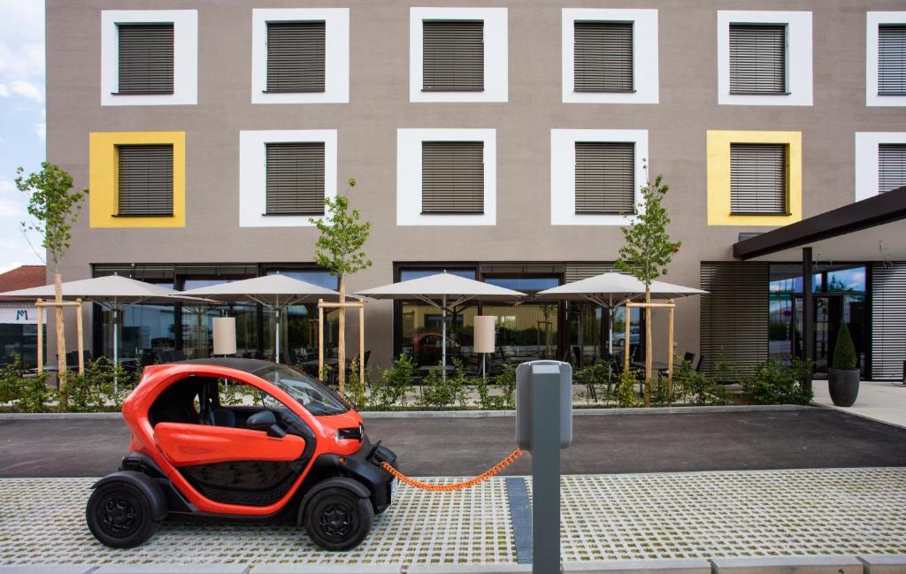 een kleine rode auto geparkeerd voor een gebouw bij Hotel am Campus in Ingolstadt