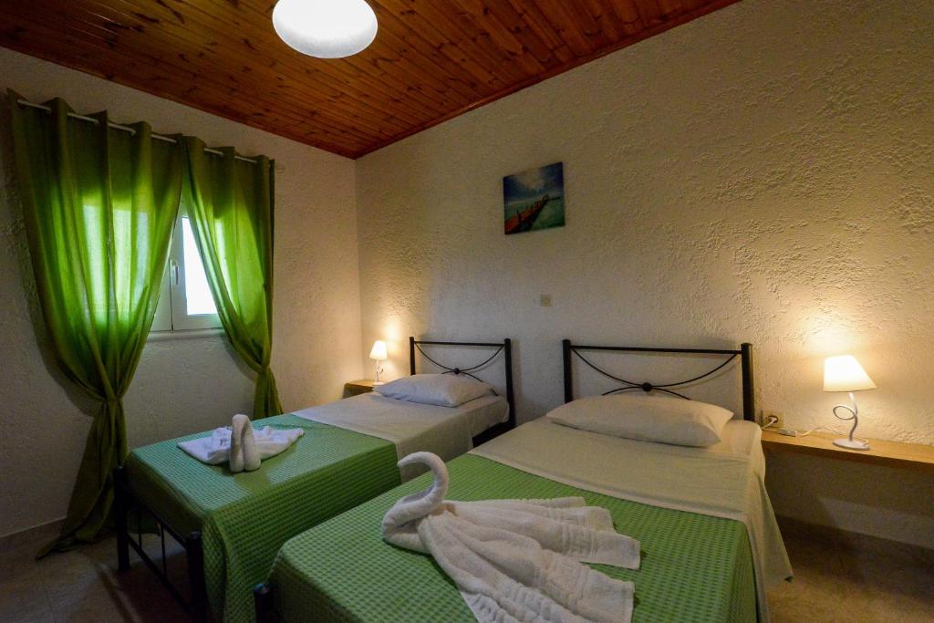 2 Betten in einem Zimmer mit grünen Vorhängen in der Unterkunft Villa Fantasea in Plimmiri