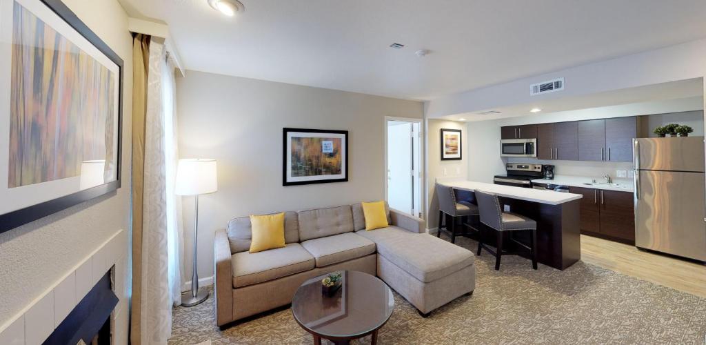 a living room with a couch and a kitchen at Chase Suite Hotel Newark Fremont in Newark