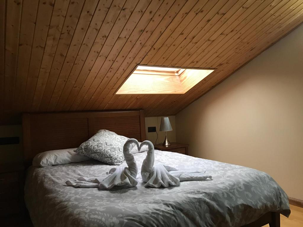Dos cisnes blancos acostados en una cama en un dormitorio en Apartamentos Vista Sierra Nevada, en Sierra Nevada