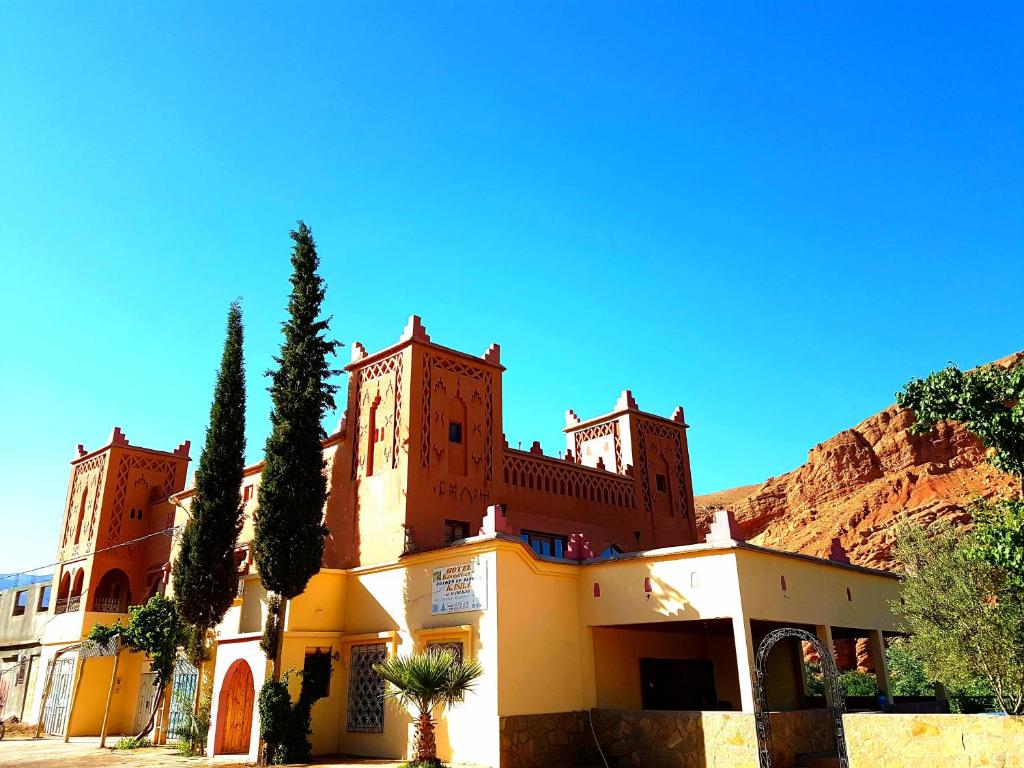 a large building with trees in front of a mountain at Auberge Kasbah Ait Marghad in Tamellalt
