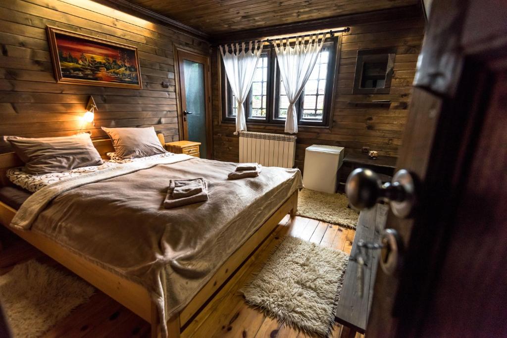 a bedroom with a bed in a room with wooden walls at Banskovilla Zlateva House in Bansko