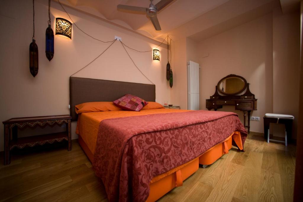 a bedroom with a large bed with an orange blanket at Amarain Casa Rural in Gestalgar