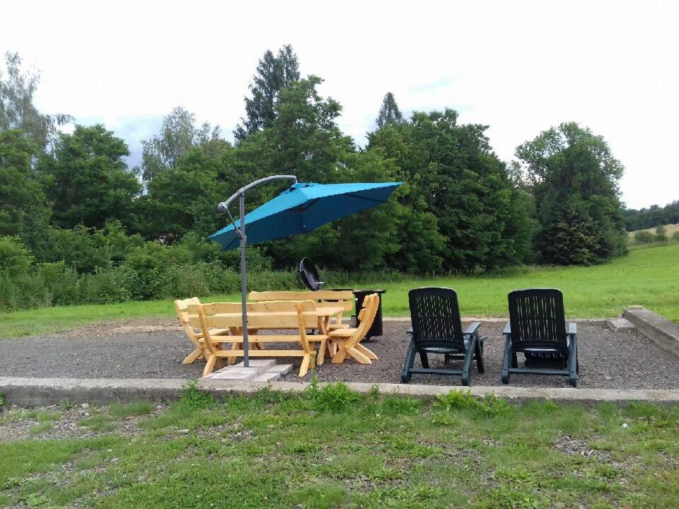 a wooden table and chairs with a blue umbrella at Łabudówka in Polańczyk