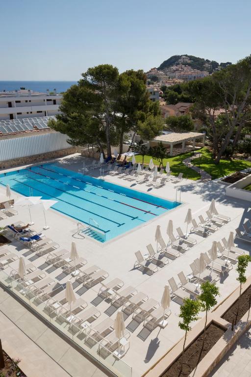 Draufsicht auf ein Schwimmbecken mit Liegestühlen und einer Pool-Sonnenblende in der Unterkunft Hotel Bella Playa & Spa in Cala Ratjada